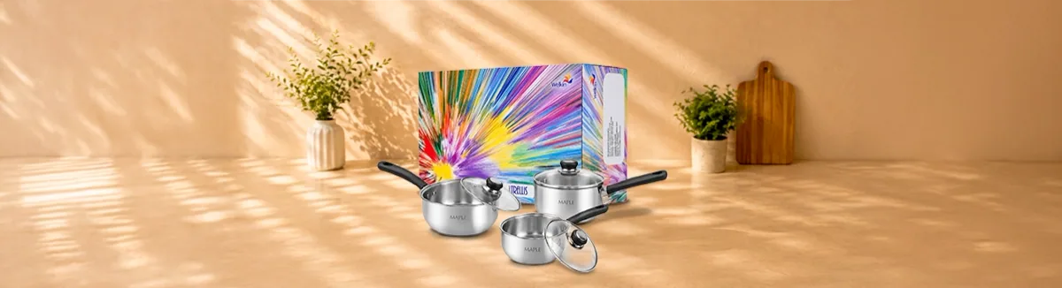 Three steel saucepans with glass lids before a colourful gift box