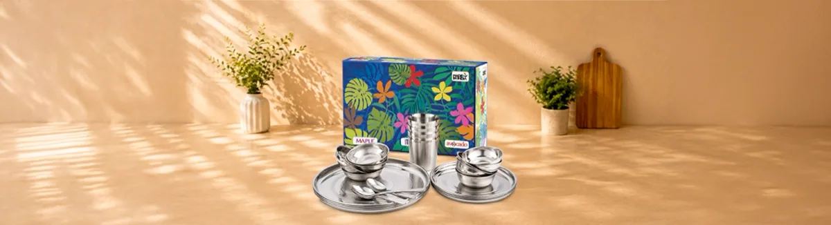 Steel thalis, bowls, spoons and tumblers laid out before a printed gift box