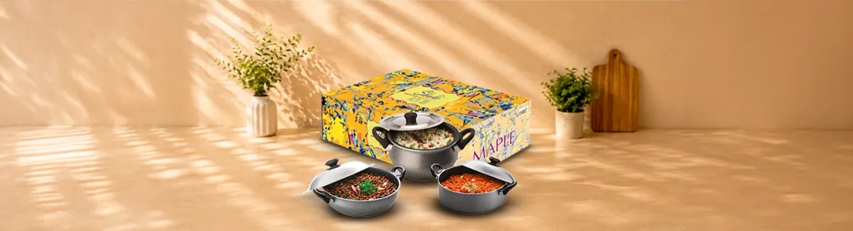 Three grey non-stick pots with steel lids, holding food, before a yellow box
