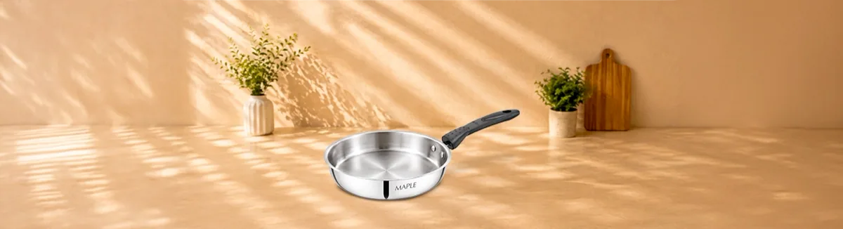 Steel fry pan with a black handle on a sunlit counter