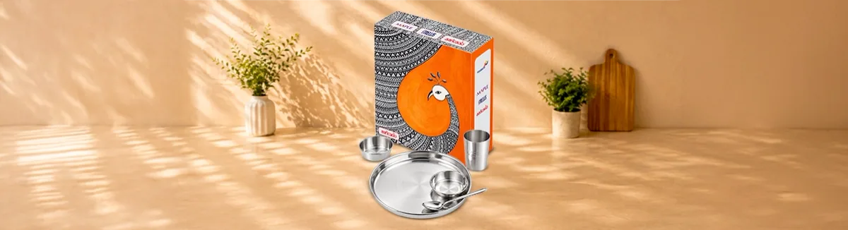 Steel plate, two bowls, a tumbler and a spoon before a peacock-print box