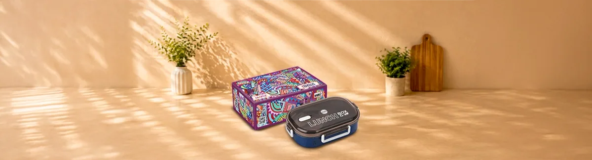Navy lunch box with a black clip-shut lid, beside its patterned carton